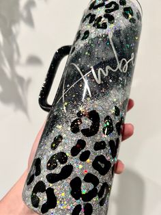 a hand holding a black and silver leopard print water bottle