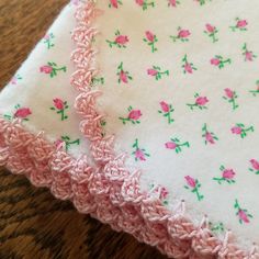 two pieces of cloth with pink flowers on them sitting on top of a wooden table