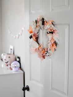 a white door with a wreath hanging on it's side next to a teddy bear