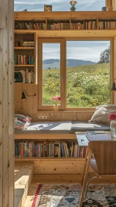 there is a window in the room that has books on it and a desk with a chair next to it