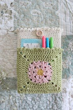 a crocheted bag with markers and pens on it sitting on a quilted surface