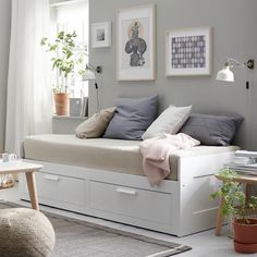 a white daybed sitting in a living room next to a chair and table with potted plants on it