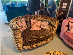 a man standing next to a tiger print couch and chair in a room filled with furniture