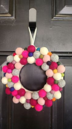 a wreath with pom - poms hanging from the front door