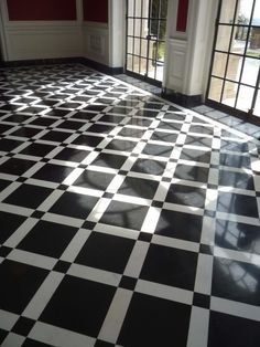 a black and white checkered floor in an empty room with large doors leading to the outside