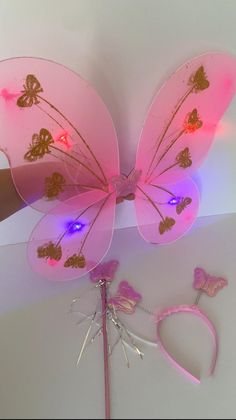 a pink butterfly shaped object with lights on it's wings and two small hair clips