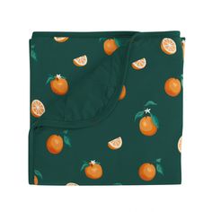 an orange print blanket on a white background with green leaves and oranges all over it