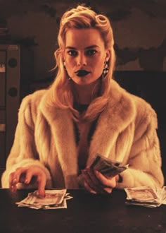 a woman sitting at a table with money in front of her and wearing a fur coat