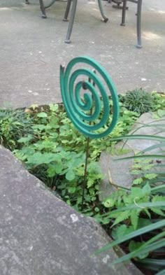 a green sculpture sitting in the middle of a garden next to some benches and tables