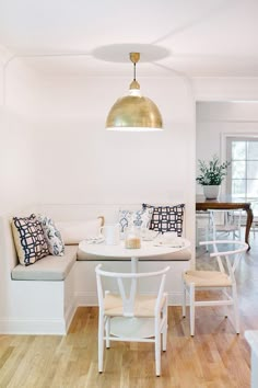 a white table and chairs in a room with wood floors, light fixture over the dinning area