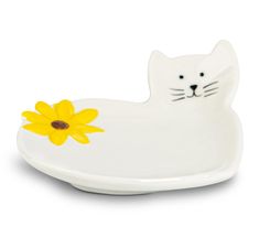 a white cat shaped dish with a yellow flower in it's mouth on a white background