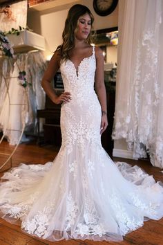 a woman in a white wedding dress standing on a wooden floor with her hands on her hips