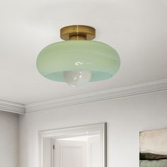 a room with white walls and a green light fixture hanging from the ceiling in front of a door