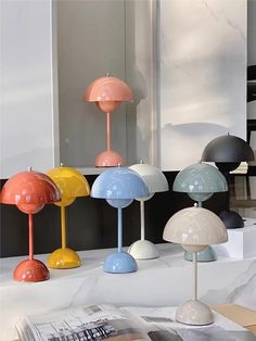 several different colored lamps on display in a room with white walls and black flooring