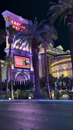 the las vegas hotel and casino is lit up at night with palm trees in front