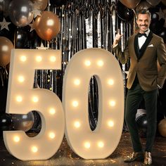 a man in a tuxedo standing next to the number 50