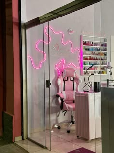 a pink office chair sitting in front of a glass door with neon lights on it