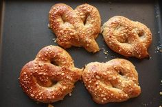 four pretzels on a baking sheet with sesame seeds sprinkled all over them