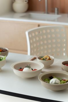 four bowls with different types of food in them sitting on a counter top next to a sink