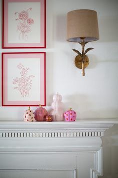 two framed pictures on the wall above a mantle with candles and other items in front of it