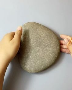 two hands are touching a rock with their fingers