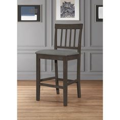 a wooden chair sitting on top of a hard wood floor next to a framed painting