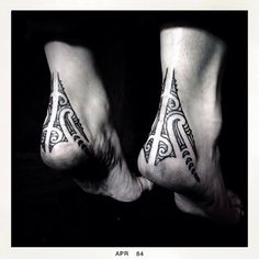 two people with tattoos on their feet standing next to each other in black and white