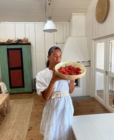 a woman holding a bowl with strawberries in it