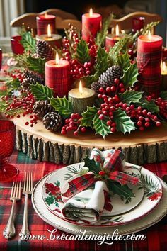 a christmas table setting with candles, holly wreaths and pine cones on the centerpiece