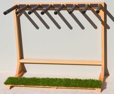 a wooden bench with grass on the bottom and metal rods hanging from it's sides