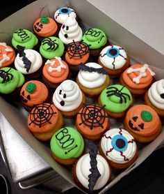 a box filled with lots of cupcakes covered in frosting and decorated to look like halloween decorations