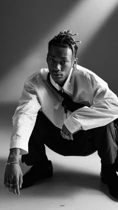 a black and white photo of a man in a shirt and tie crouching down