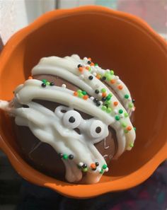 an orange cup filled with white frosting and sprinkles on top of each other