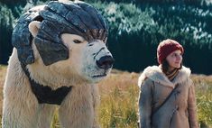 a woman standing next to a large polar bear wearing a helmet on it's head