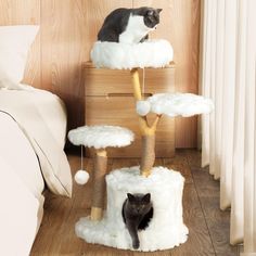 a cat sitting on top of a scratching post in a bedroom next to a bed