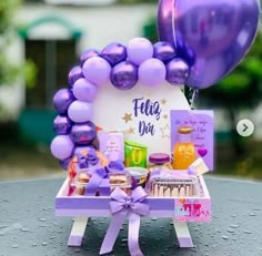 a table topped with purple balloons and cake