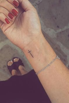 a woman's wrist with a small cross tattoo on the left side of her arm