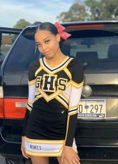 a girl in a cheer uniform standing next to a car