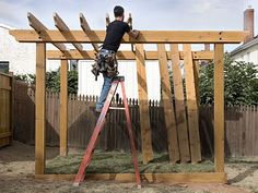 a man on a ladder working on a wooden structure