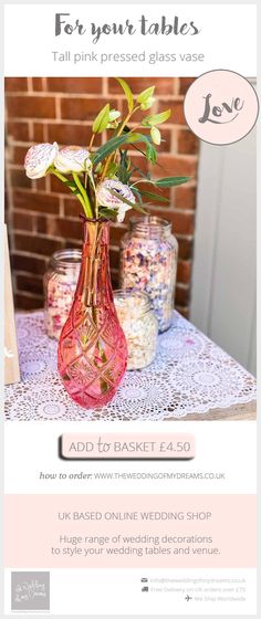 a pink vase filled with flowers sitting on top of a table next to two jars