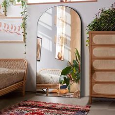 a mirror sitting on top of a wooden floor next to a bed and plant in a room