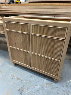 a wooden cabinet sitting on top of a floor next to a pile of wood planks