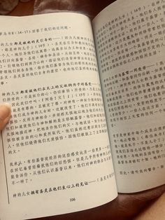 a person holding an open book in their hand with chinese characters on it and writing