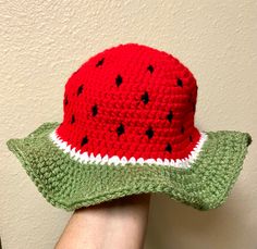 a person wearing a crocheted watermelon hat with black dots on it