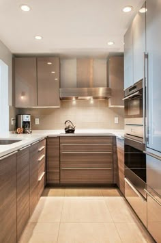 a modern kitchen with stainless steel appliances and wood cabinetry, along with tile flooring