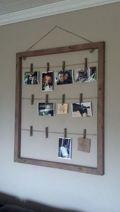 a wooden frame hanging on the wall with pictures pinned to it and clothes pins attached to them