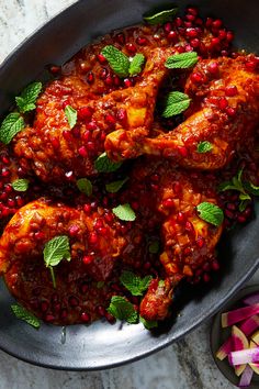 chicken with pomegranate and mint garnish in a pan