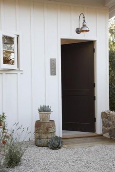 a white house with a black door and two succulents