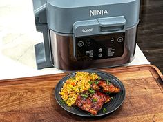 a plate of food sitting on top of a wooden cutting board next to an air fryer