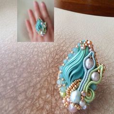 a close up of a person's hand wearing a ring with pearls on it